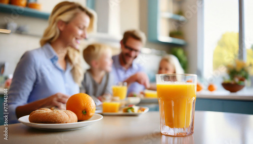 Close up of glass of orange juice on table with family in background
