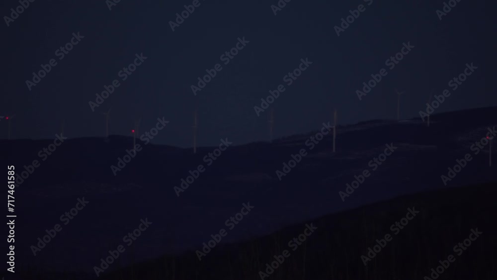 Wind turbine mill flashing red light far away on forest hill appalachian mountain at night panning left