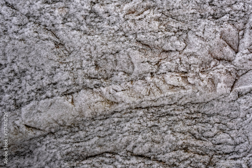 The texture of the stone cliffs covered with frost with snow. Rough aged granite stone frost covered surface. 