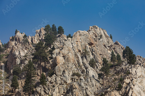 A very rocky mountain with a few trees and green patches in California against a blue sky on a Sunny Summer day. Nr.2
