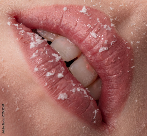 Close-up of a girl's lips in lipstick with snowflakes. Macro