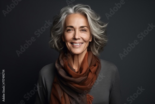 Portrait of smiling senior woman in scarf, isolated on grey background