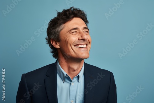 Portrait of a happy mature man laughing and looking away against blue background