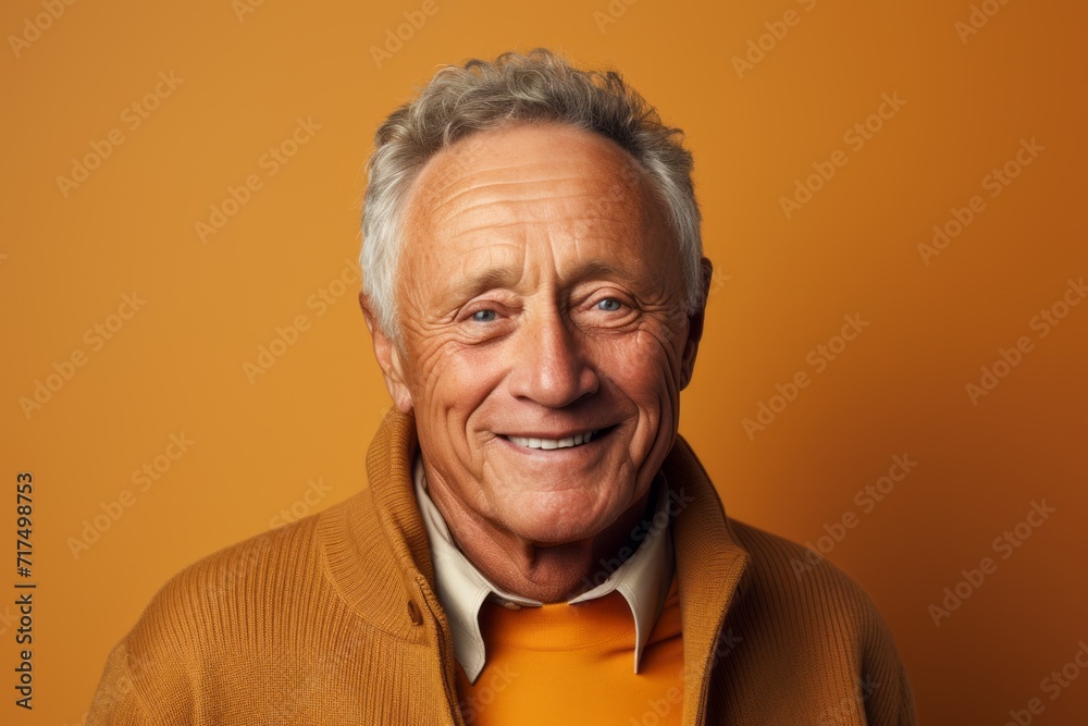 Portrait of a smiling senior man in an orange sweater on a yellow background Portrait of a smiling senior man in an orange sweater on a yellow background