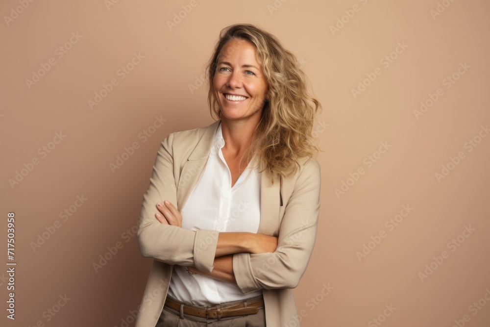 Portrait of a happy mature businesswoman with arms crossed over brown background Portrait of a happy mature businesswoman with arms crossed over brown background
