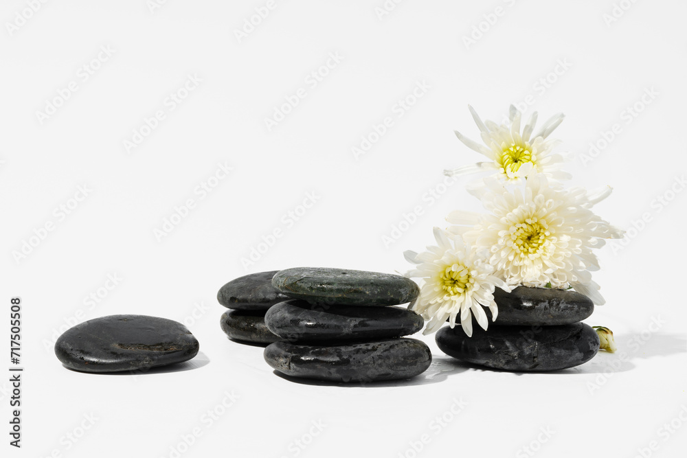 Stacked black spa stones with flowers on white background Stacked black spa stones with flowers on white background