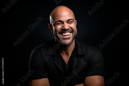 Portrait of a happy mature man laughing against a black background.
