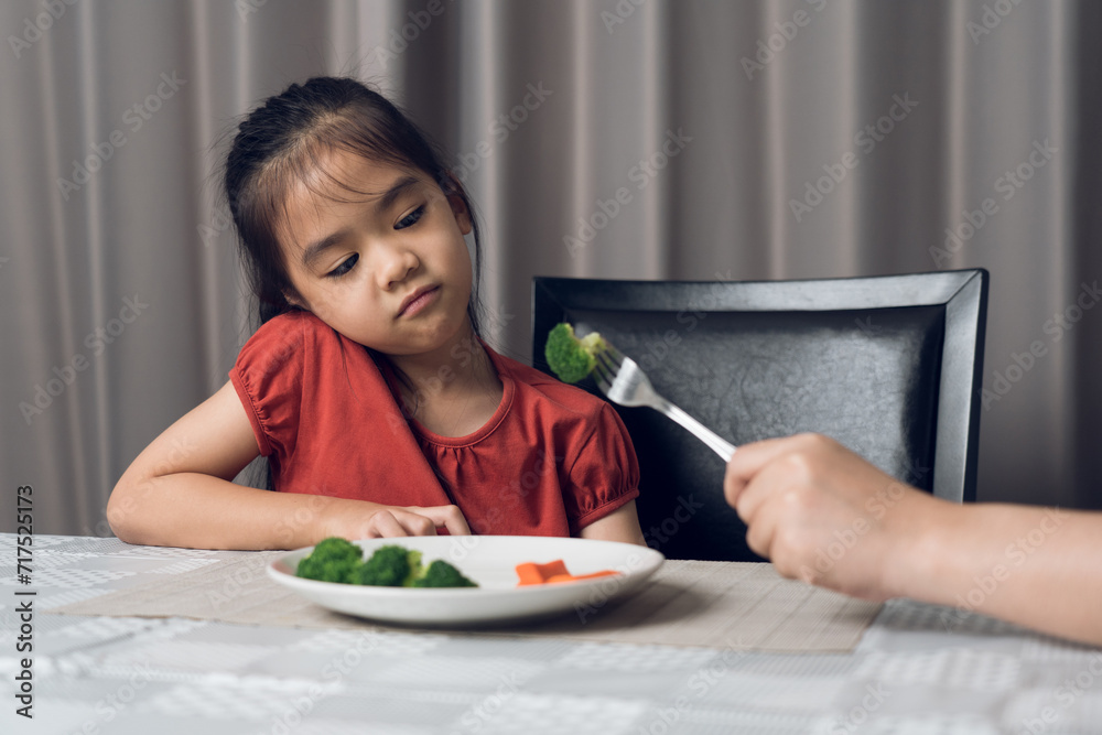 Little cute kid girl refusing to eat healthy vegetables. Children do not like to eat vegetables.