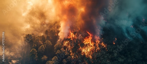 Bird's-eye view of a forest fire or wildfire captured by an aerial drone, showing dense smoke clouds and the combustion of parched vegetation. © TheWaterMeloonProjec