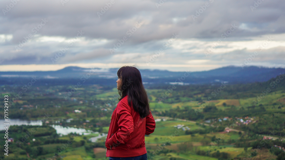 Women travel in mountains alone. Winter weather, calm scene. Backpacker walking outdoors, back view over landscape with sporty girl, green grass, forest, hills, sky, travel.