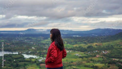 Women travel in mountains alone. Winter weather, calm scene. Backpacker walking outdoors, back view over landscape with sporty girl, green grass, forest, hills, sky, travel.