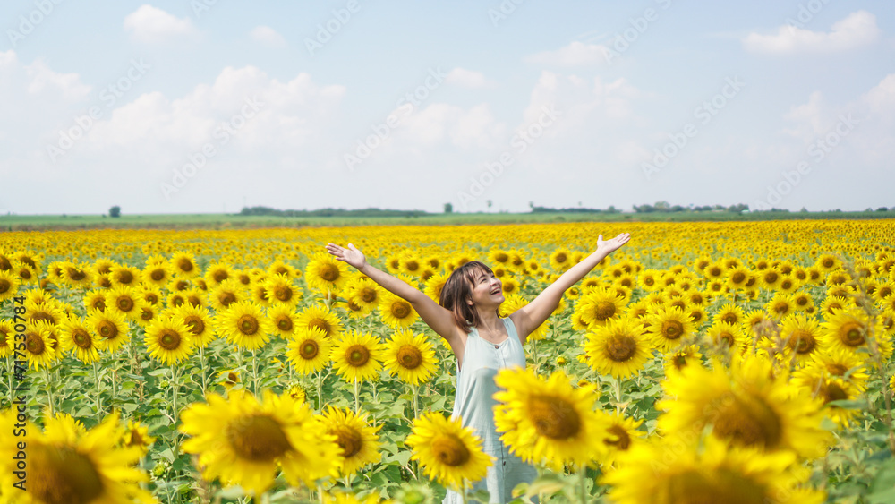Obraz premium Smile face and short hair asian woman in the field of sunflowers, standing arm raised. Portrait of a beautiful asian woman feeling happy and funny in the sunflower field.