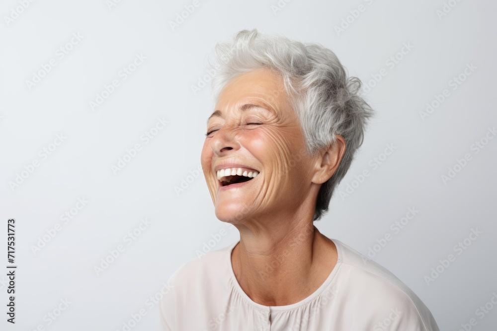 Close up portrait of a happy senior woman laughing against grey background. Close up portrait of a happy senior woman laughing against grey background.