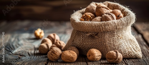 Walnuts in a rustic sack on a wooden background.