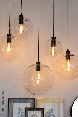 Glass transparent hanging round lamps above the table with paintings