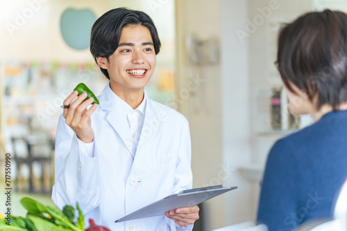 女性に野菜や果物を勧める若い白衣の男性　管理栄養士 photo