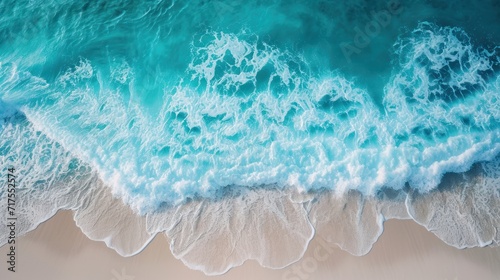 Soft waves of the blue ocean on a clean white sand beach. Top view.