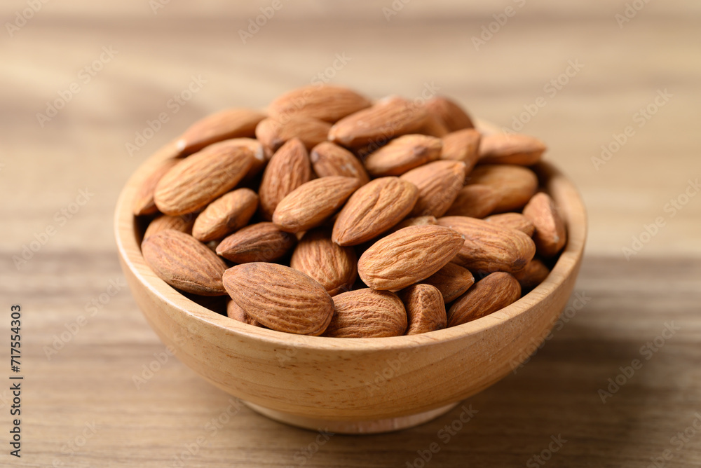 Raw almond nut in bowl on wooden background Raw almond nut in bowl on wooden background
