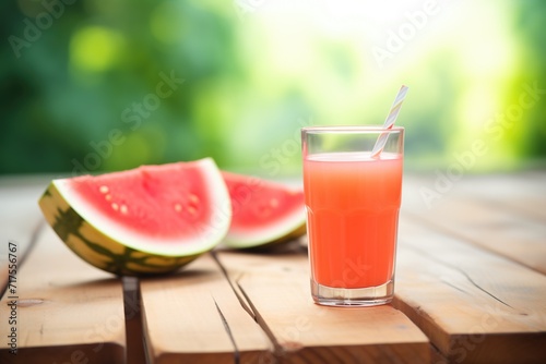 sliced watermelon beside a glass of juice on a wooden table