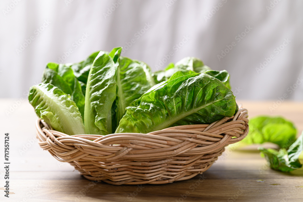 Organic cos romaine lettuce in basket on wooden table, Food ingredient for healthy salad - obrazy, fototapety, plakaty 