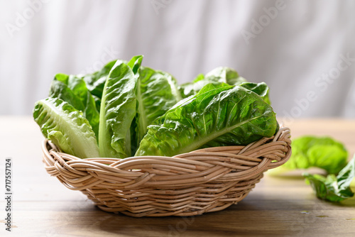 Organic cos romaine lettuce in basket on wooden table, Food ingredient for healthy salad photo