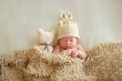 Canvas Print Cute newborn baby sleeping with a teddy bear toy and is covered with a brown cotton blanket