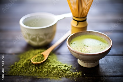 matcha latte beside a bamboo whisk and green tea powder