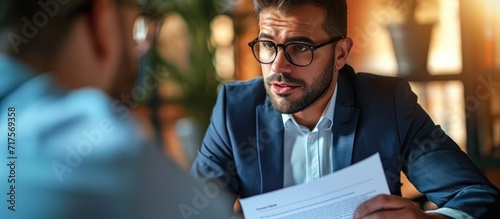 Fotografia HR manager looking suspiciously at job candidate reading cv resume of male appli