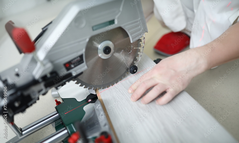 Man uses circular saw table while cutting laminate. Laminate laying technology with Click lock. Features of sawing laminate. Flooring option. Imitation shades and textures various types wood Man uses circular saw table while cutting laminate. Laminate laying technology with Click lock. Features of sawing laminate. Flooring option. Imitation shades and textures various types wood