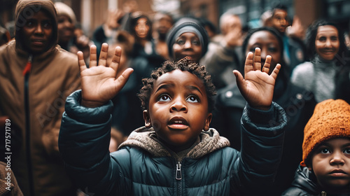 A black child with hands raised with a background of people demonstrating