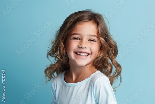 Portrait of a cute smiling little girl on a blue background. © Iigo