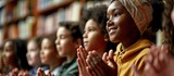 Multiethnic group of kids sitting on floor near teacher and applauding Diverse schoolchildren having lesson in school library and clapping hands thanking teacher. Copy space image