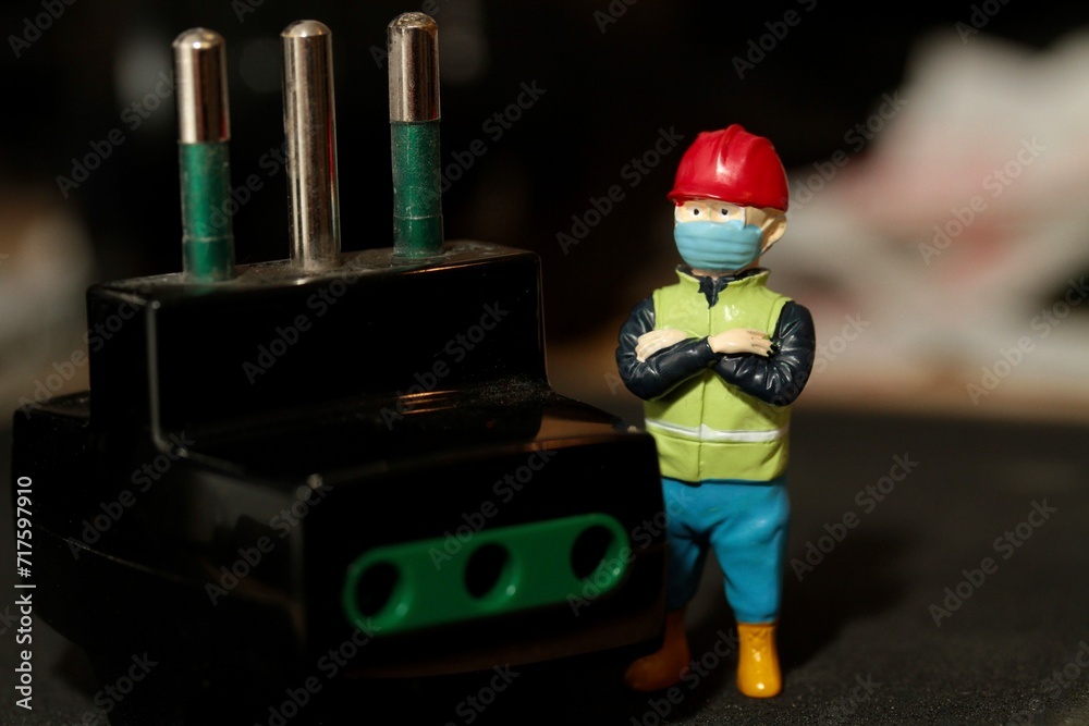 miniature figurine of an electrician with an electric plug