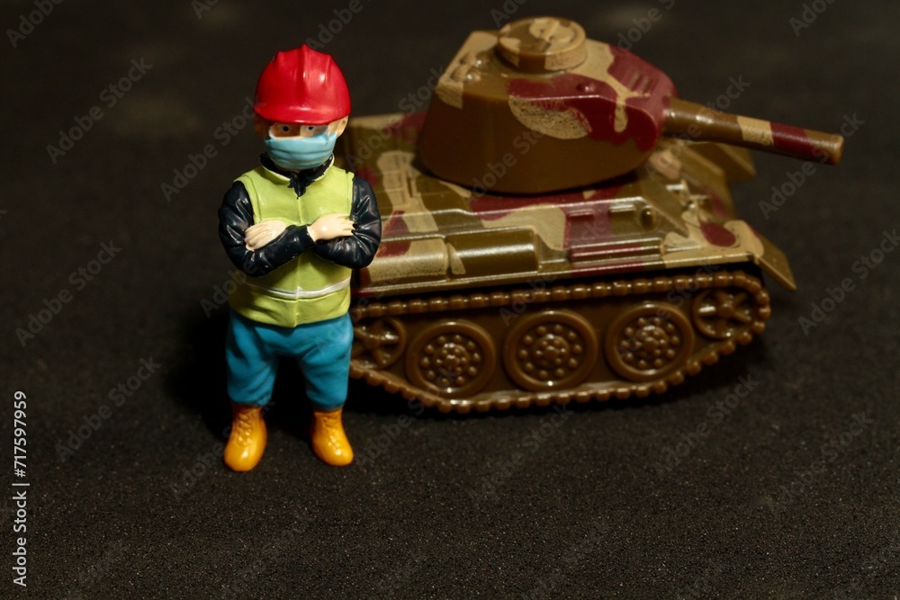 Fototapeta premium miniature worker with a war military tank
