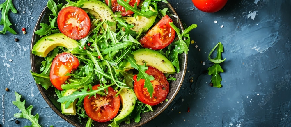 Top view of a nutritious vegan salad with avocado, tomato, and arugula. Top view of a nutritious vegan salad with avocado, tomato, and arugula.