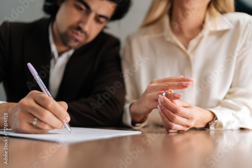 Fényképezés Cropped shot of sad spouses couple signing decree papers getting divorced in lawyers office at desk