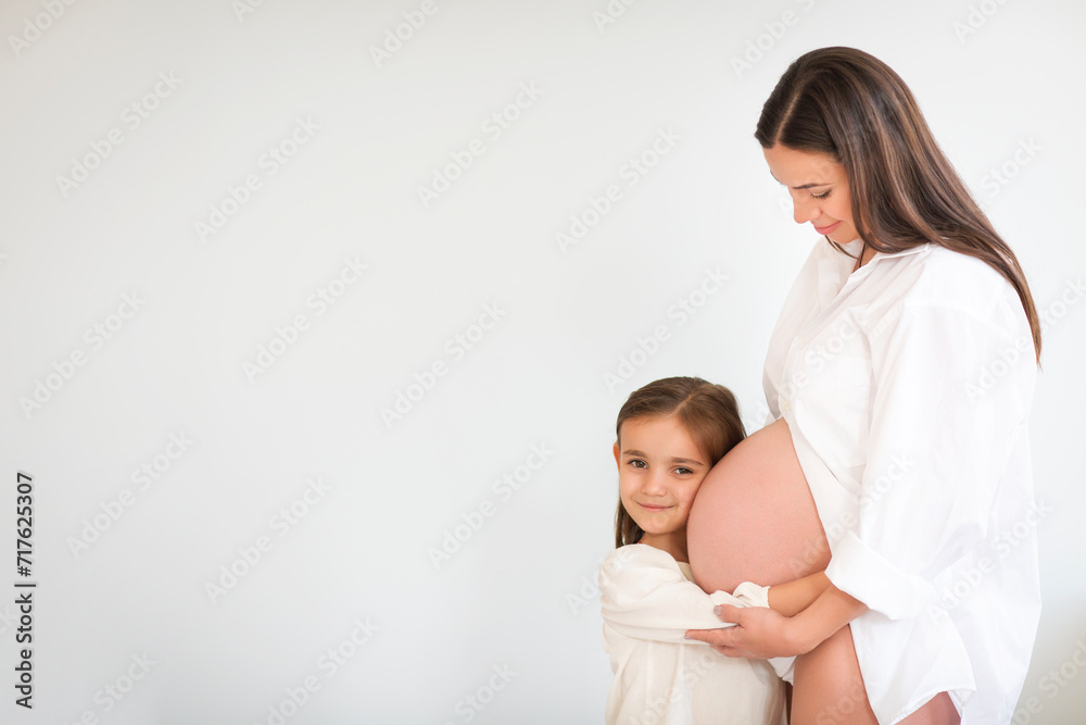 Young pretty pregnant woman and her little daughter Young pretty pregnant woman and her little daughter