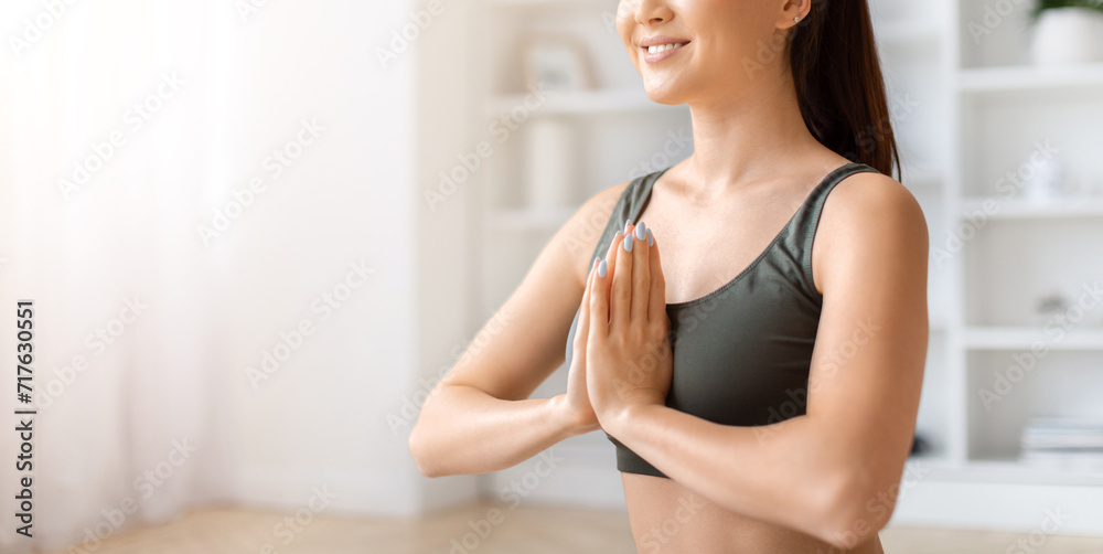 Joyful asian woman making prayer pose while meditating at home