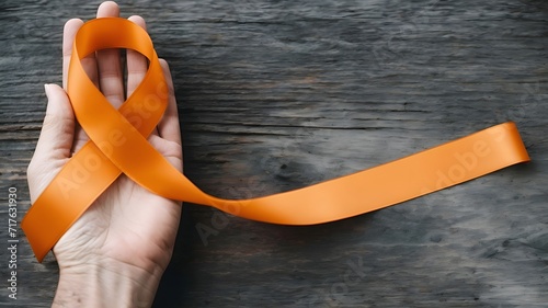Orange ribbon on old wood background raising awareness on leukemia, kidney cancer, RSD multiple sclerosis Satin fabric color symbolic concept for public support on people living with tumor disease photo