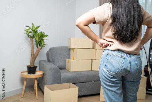 A young woman stands in front of a bunch of cardboard boxes.