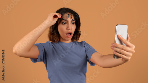 Shocked young arab woman looking at smartphone screen