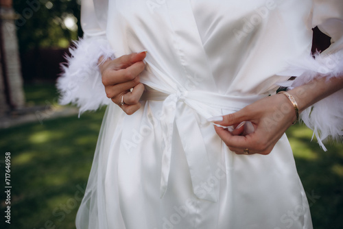 young bride tying white satin robe