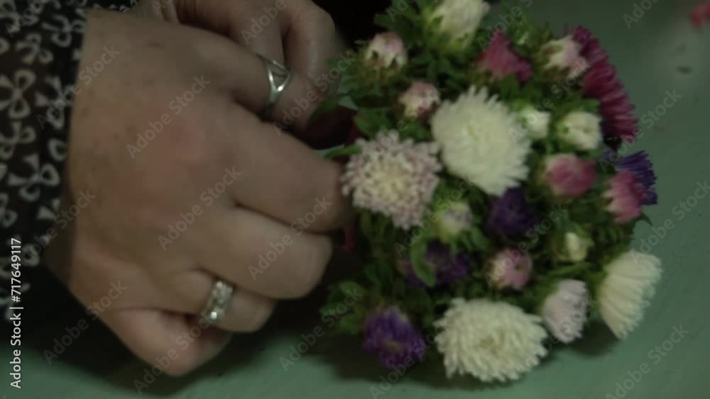 a female florist, a flower shop, ties a bouquet of chrysanthemum flowers with a ribbon a female florist, a flower shop, ties a bouquet of chrysanthemum flowers with a ribbon