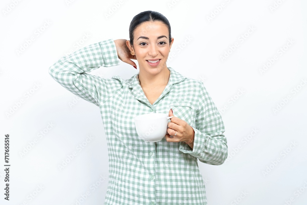 Satisfied Beautiful young woman wearing green plaid pyjama and holding a cup hold hands behind head relaxing Satisfied Beautiful young woman wearing green plaid pyjama and holding a cup hold hands behind head relaxing