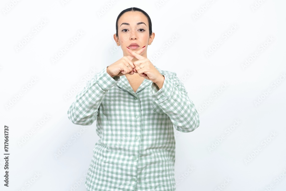 Beautiful young woman wearing green plaid pyjama Has rejection angry expression crossing fingers doing negative sign. Beautiful young woman wearing green plaid pyjama Has rejection angry expression crossing fingers doing negative sign.