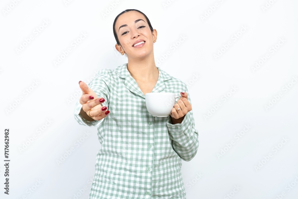 Beautiful young woman wearing green plaid pyjama smiling friendly offering handshake as greeting and welcoming. Successful business. Beautiful young woman wearing green plaid pyjama smiling friendly offering handshake as greeting and welcoming. Successful business.