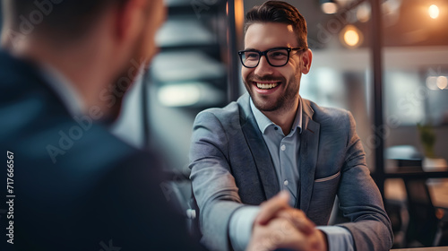Business, career, and placement concept a prosperous young man shaking hands and grinning with a businessman from Europe following productive office interviews or negotiations
