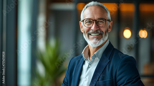 Mature entrepreneur headshot image of a smiling elder bank manager or investor, content middle-aged businessman boss CEO, and self-assured mid-adult professional businessman executive standing in offi