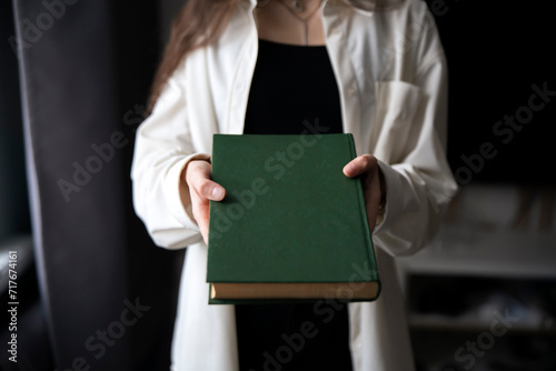 Φωτογραφία Close-Up of a Person's Hands Offering a Green hardcover Book Indoors