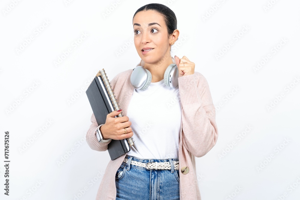 Young beautiful woman wearing white turtleneck sweater clenches fists and awaits for something nice happened looks away bites lips and waits announcement of results Young beautiful woman wearing white turtleneck sweater clenches fists and awaits for something nice happened looks away bites lips and waits announcement of results